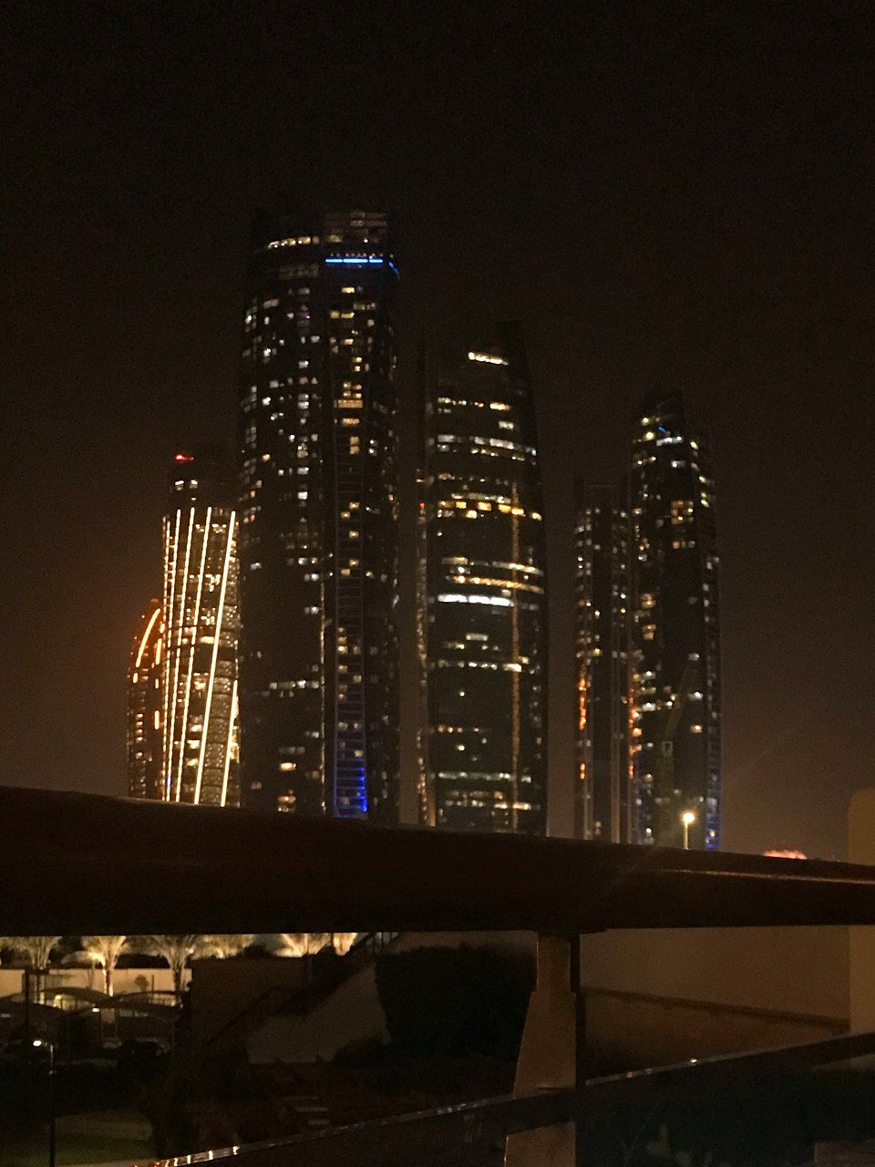 Towers of Abu Dhabi lit up at night, seen from a terrace